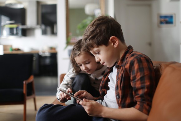Two children playing on an iPad.