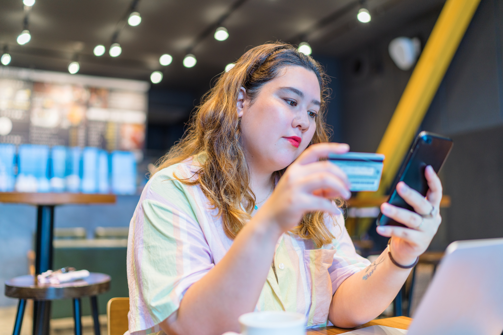 A person looking at their phone, holding a credit card.