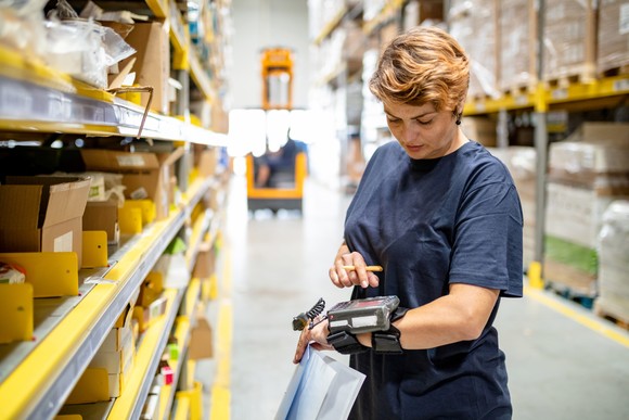 A worker using an electronic device inside a warehouse.