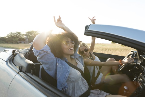 Two people driving in a convertible car.
