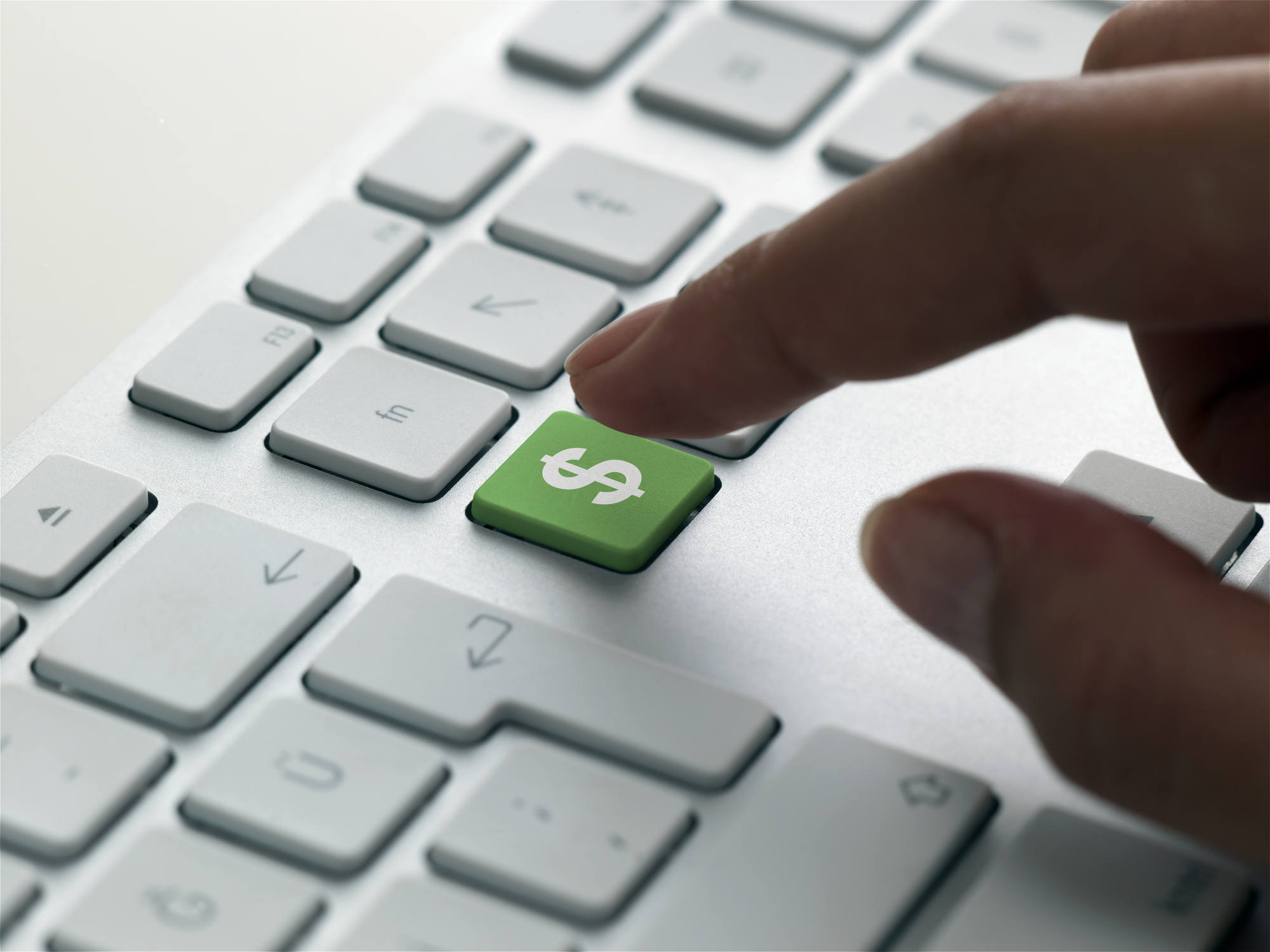 Finger about to press a green dollar sign key on a PC keyboard