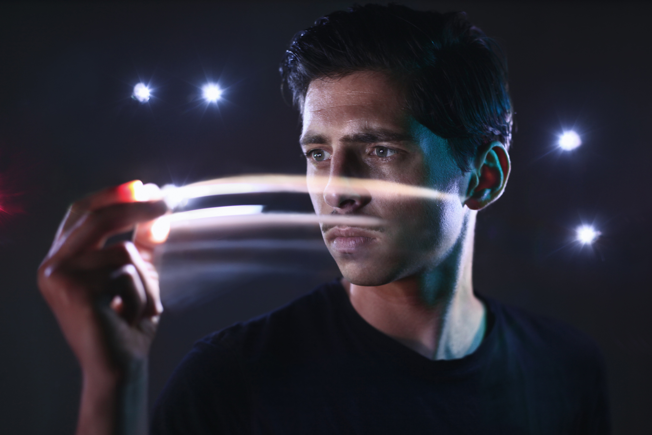Young man looks at his fingers out of which electricity shoots.
