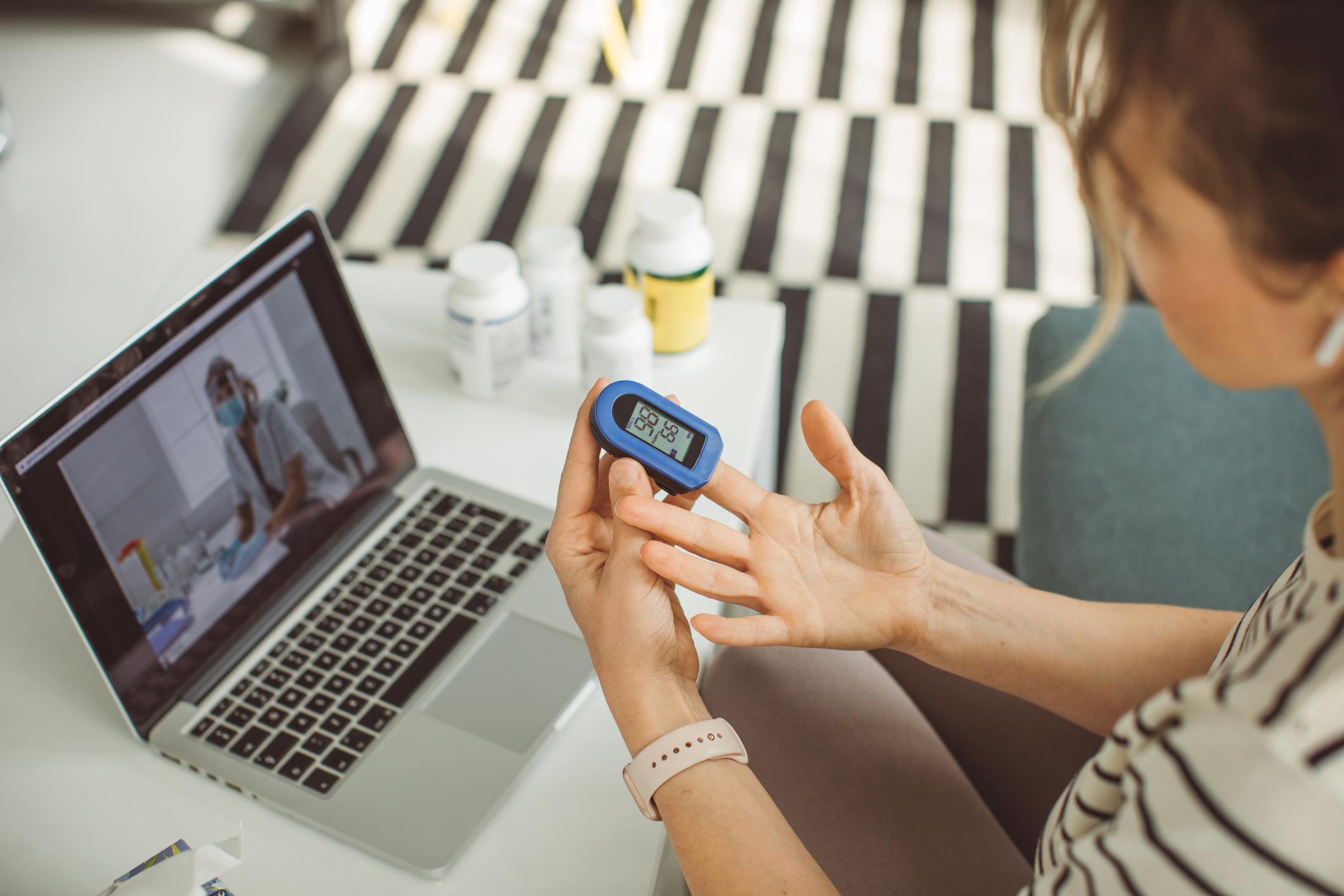 A person using pluse oximeter during telehealth discussion with doctor.