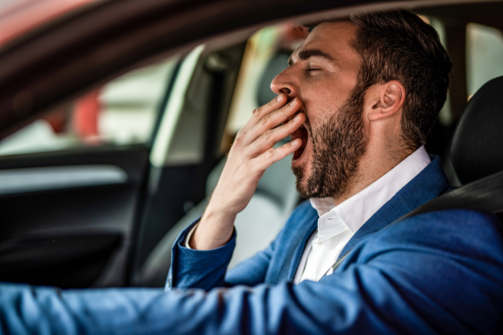 Person yawning while driving a car.