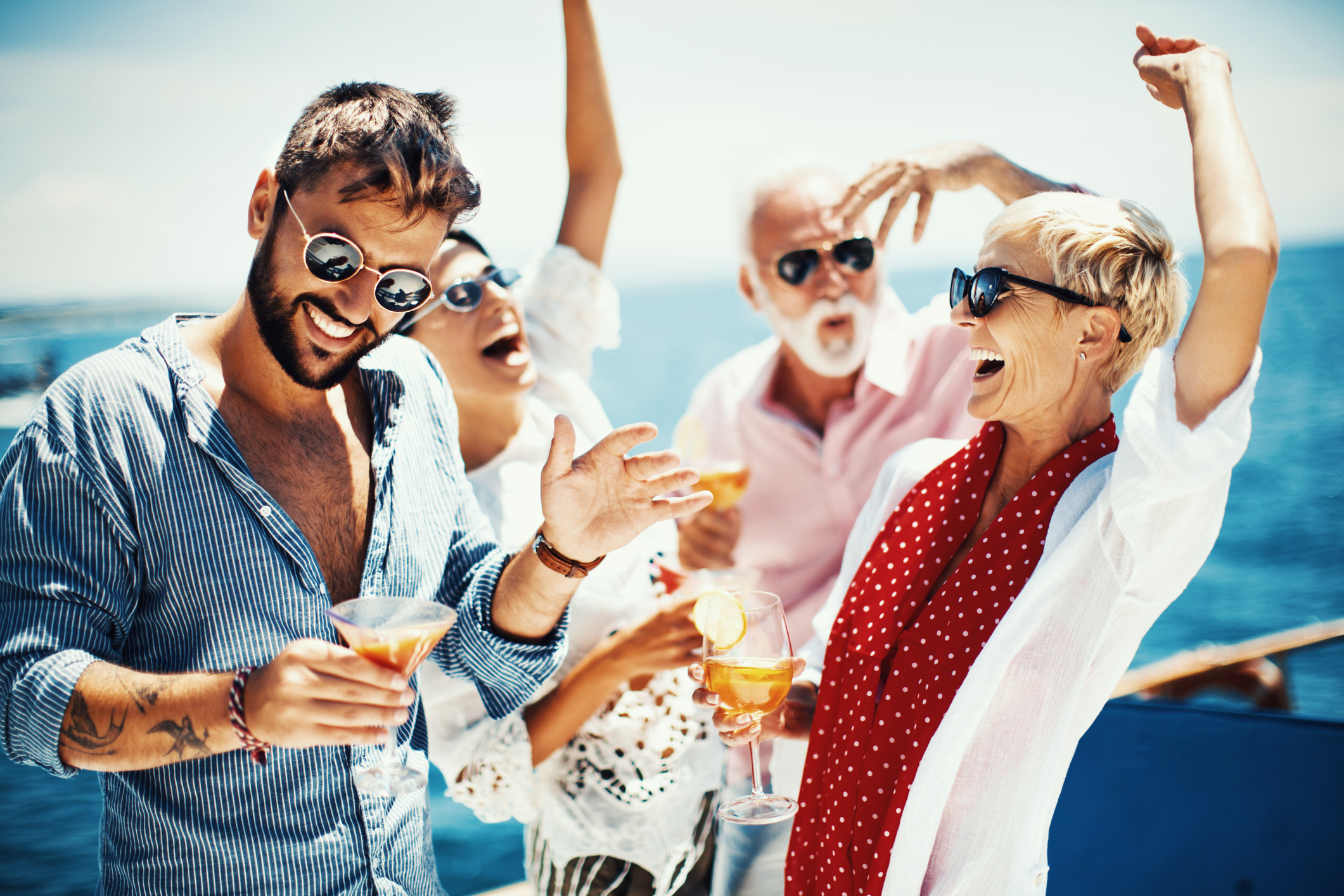 Passengers on a cruise ship hold drinks and celebrate.