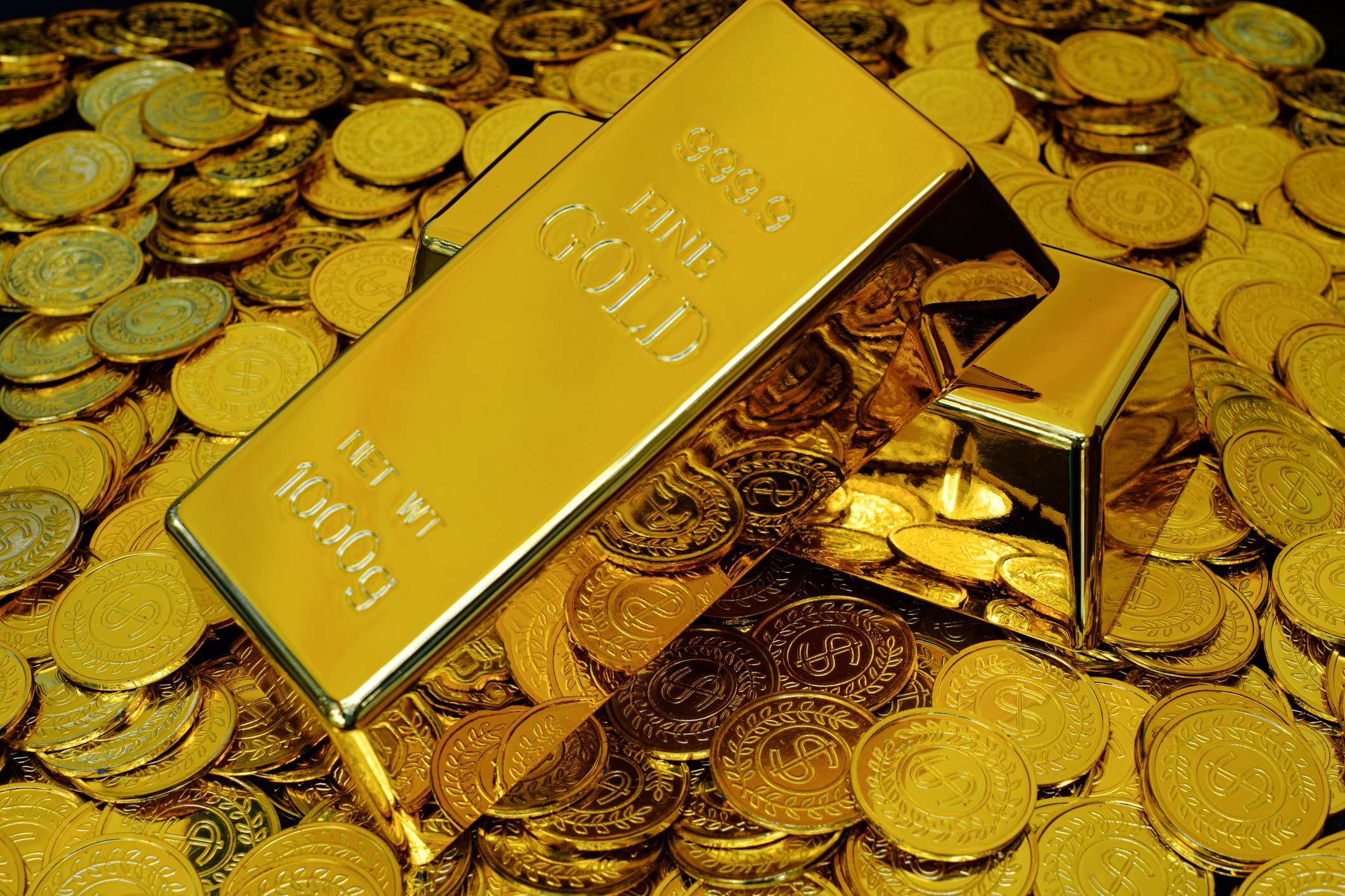 A gold bar on a pile of gold coins.