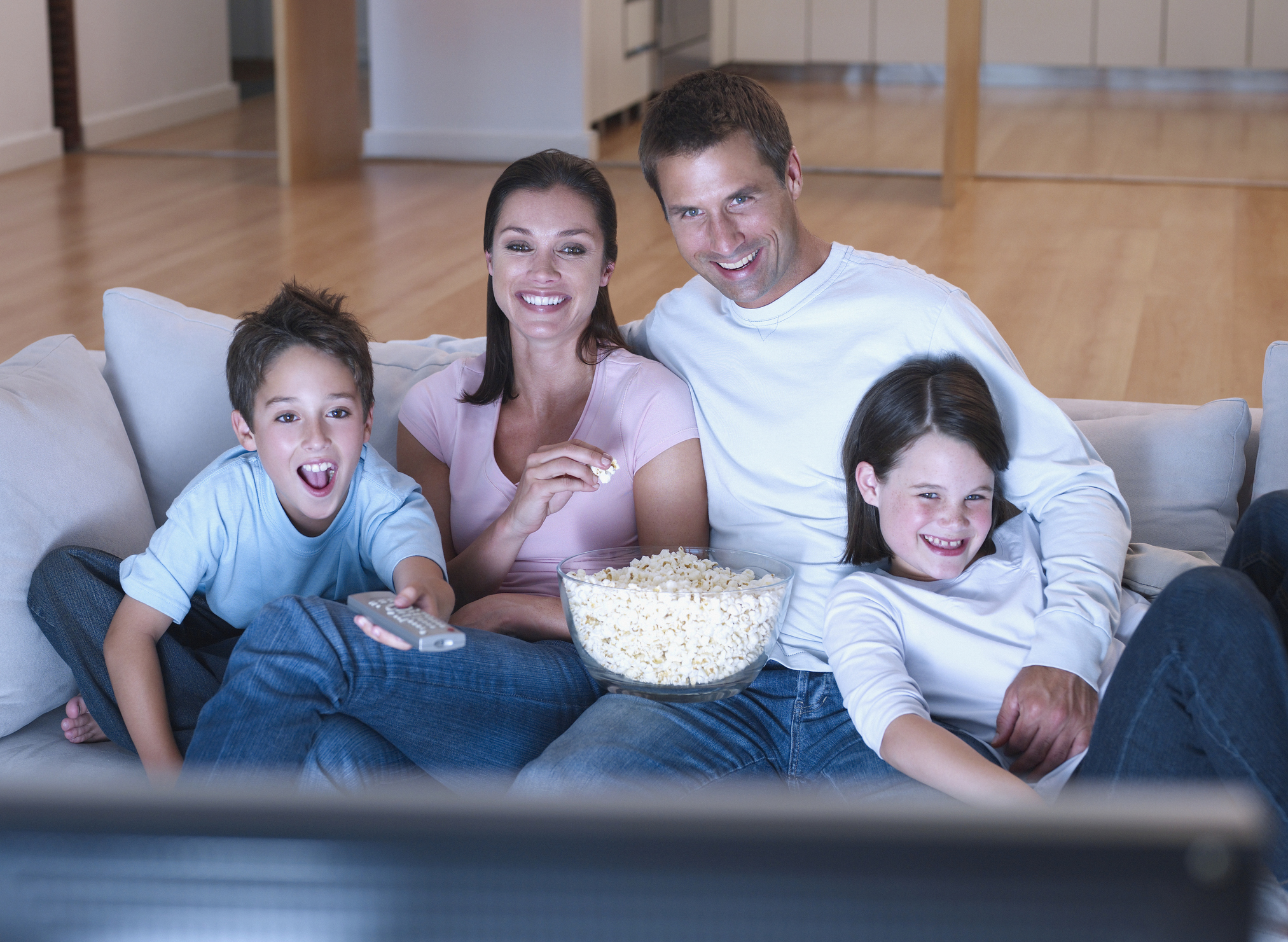 A family watching television and eating popcorn.