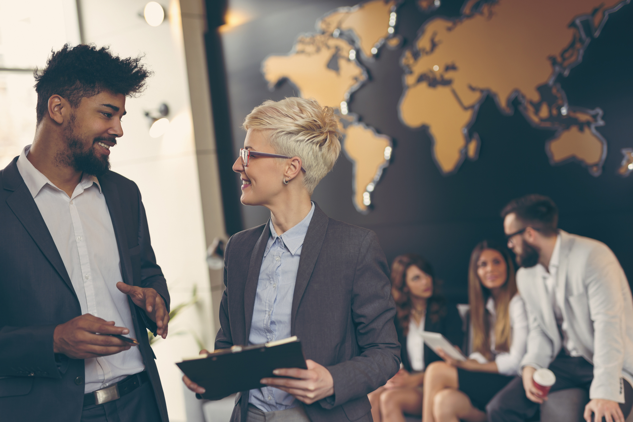 Diverse group of businesspeople in front of a map of the globe.