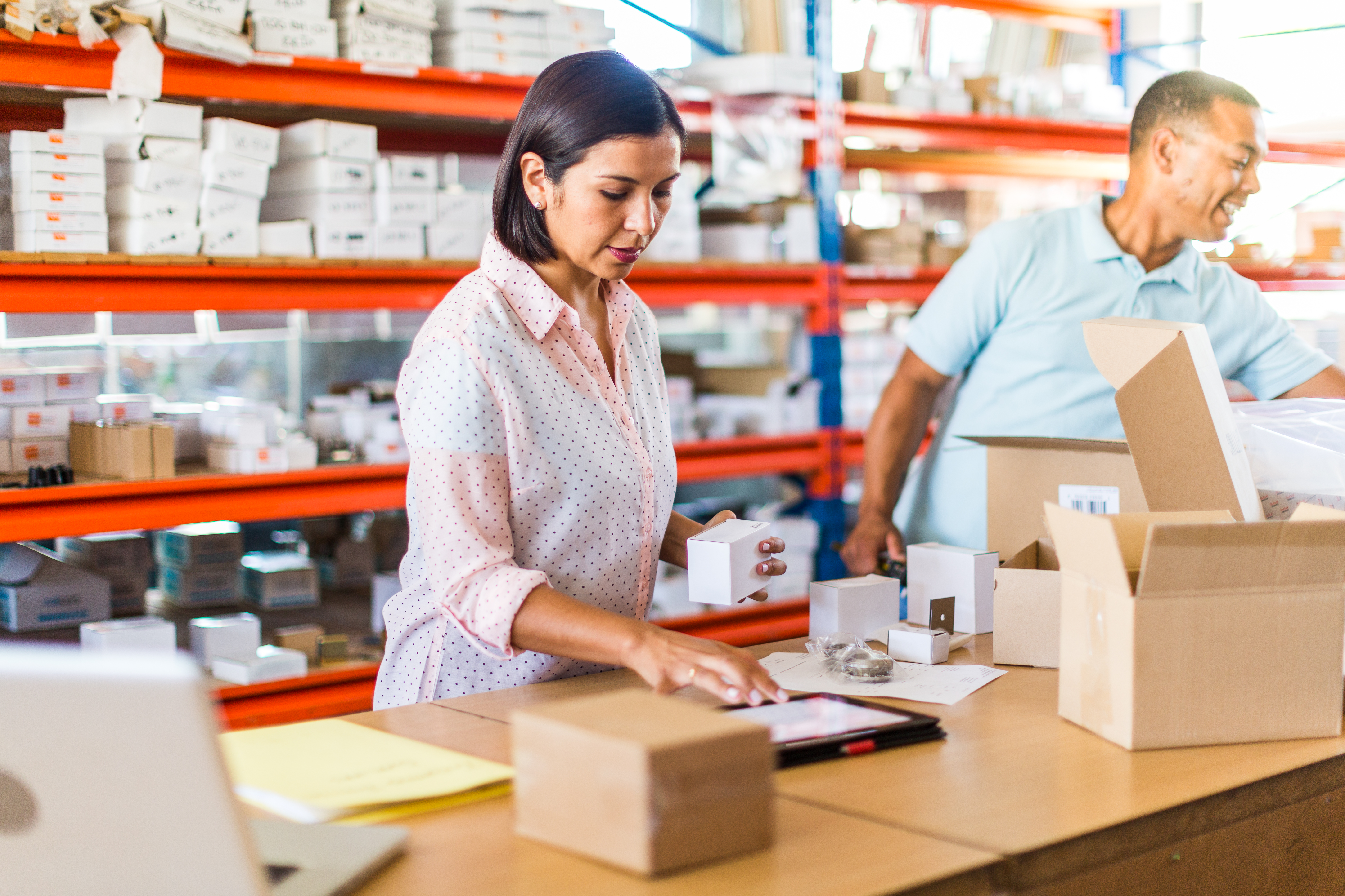 Two people packing boxes in a warehouse.