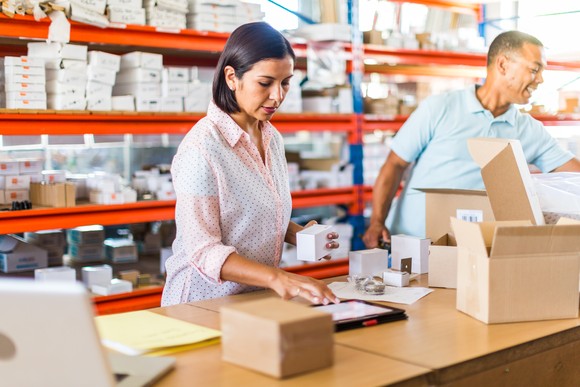 Two people packing boxes in a warehouse.