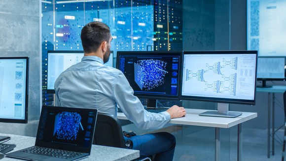 Person looking at data on computer screens.