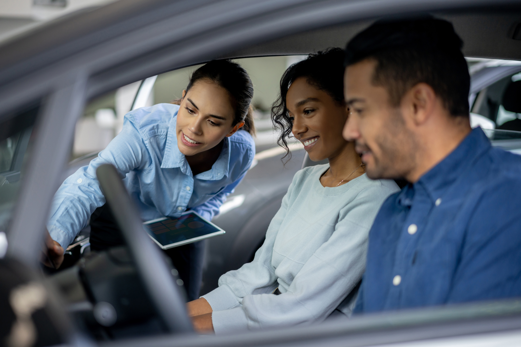 Sales person showing a vehicle to a couple.