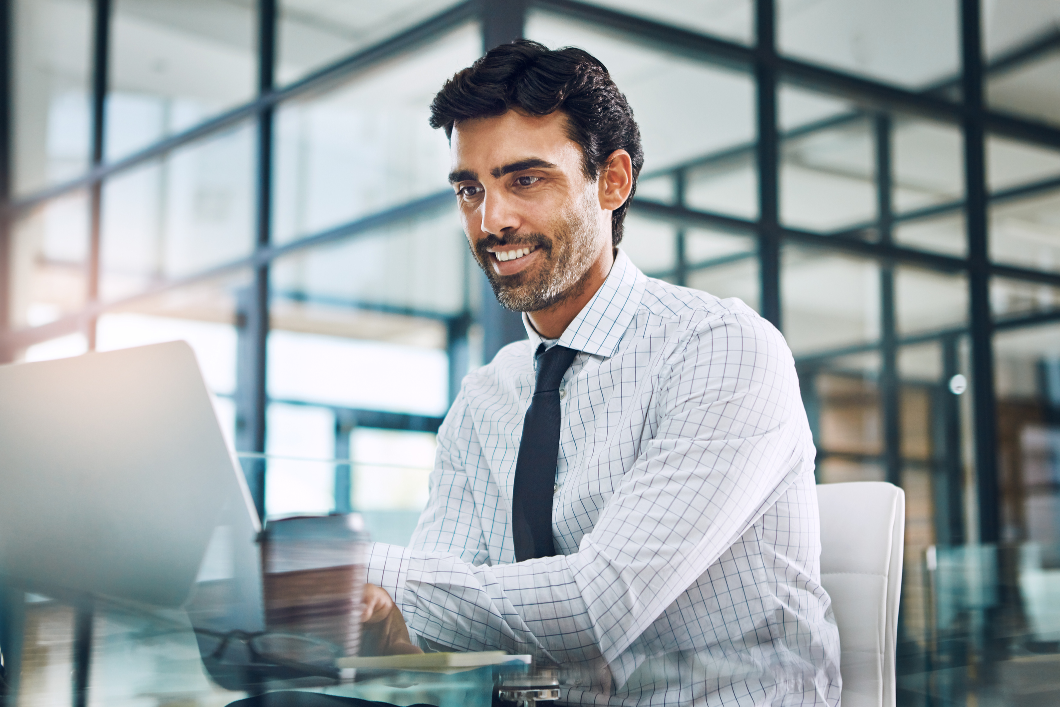 A smiling professionally dressed person at a laptop.