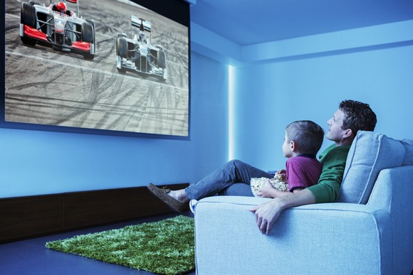 Two people watching television and eating popcorn.