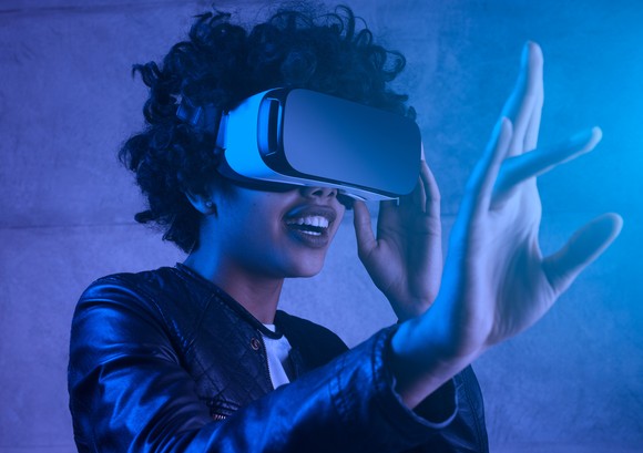 A person wearing a virtual reality headset who's putting a hand out to interact with virtual surroundings. 