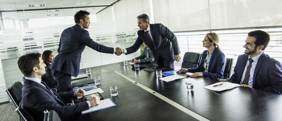People are shaking hands in a conference room. 