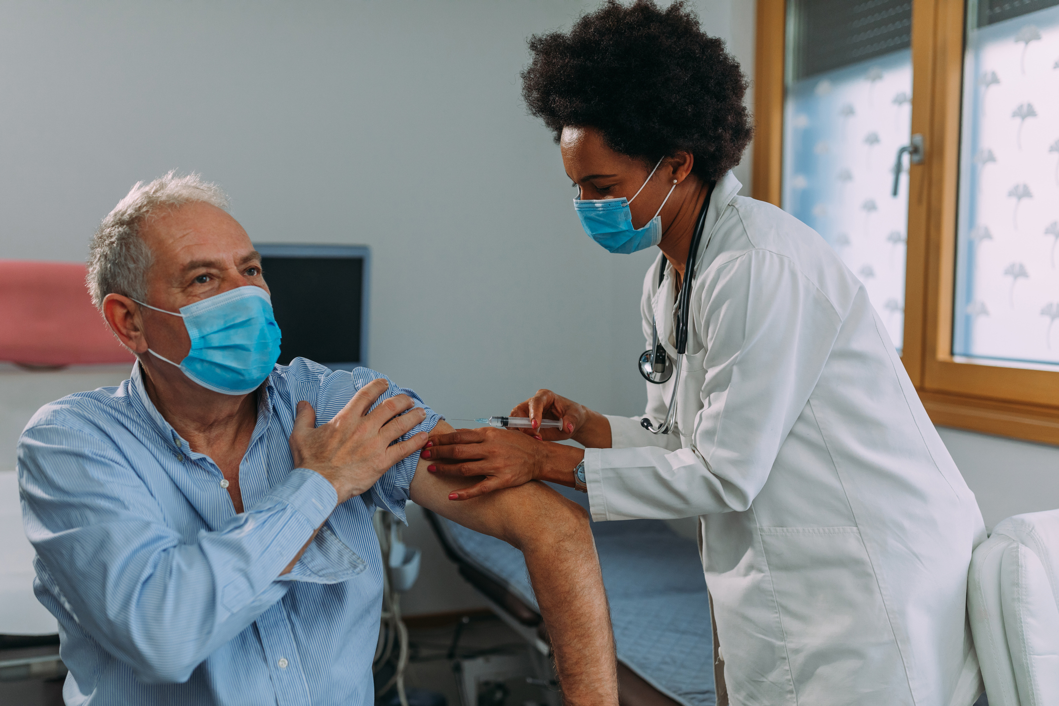 A healthcare professional giving a shot to an older person.