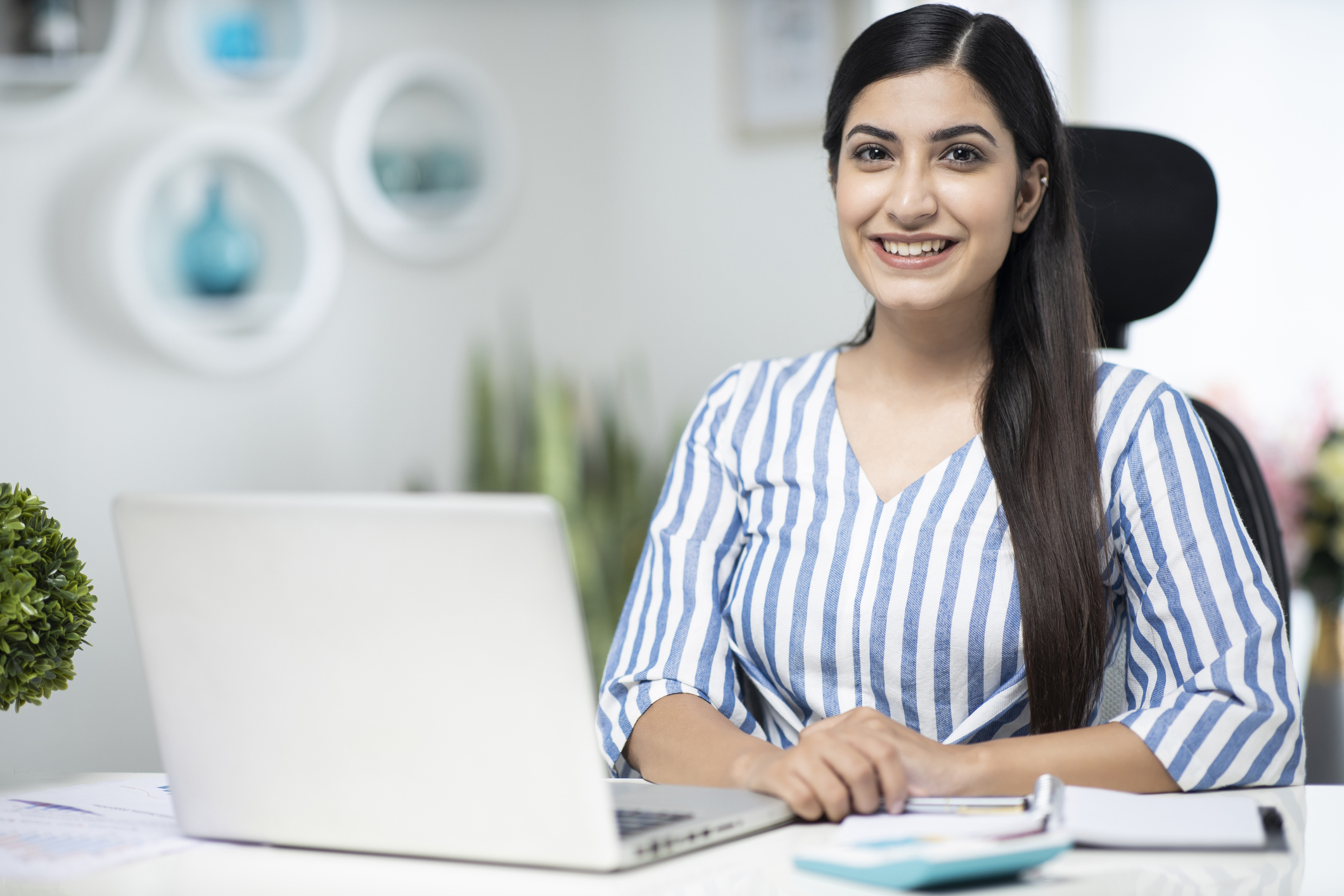 A smiling person at a laptop.