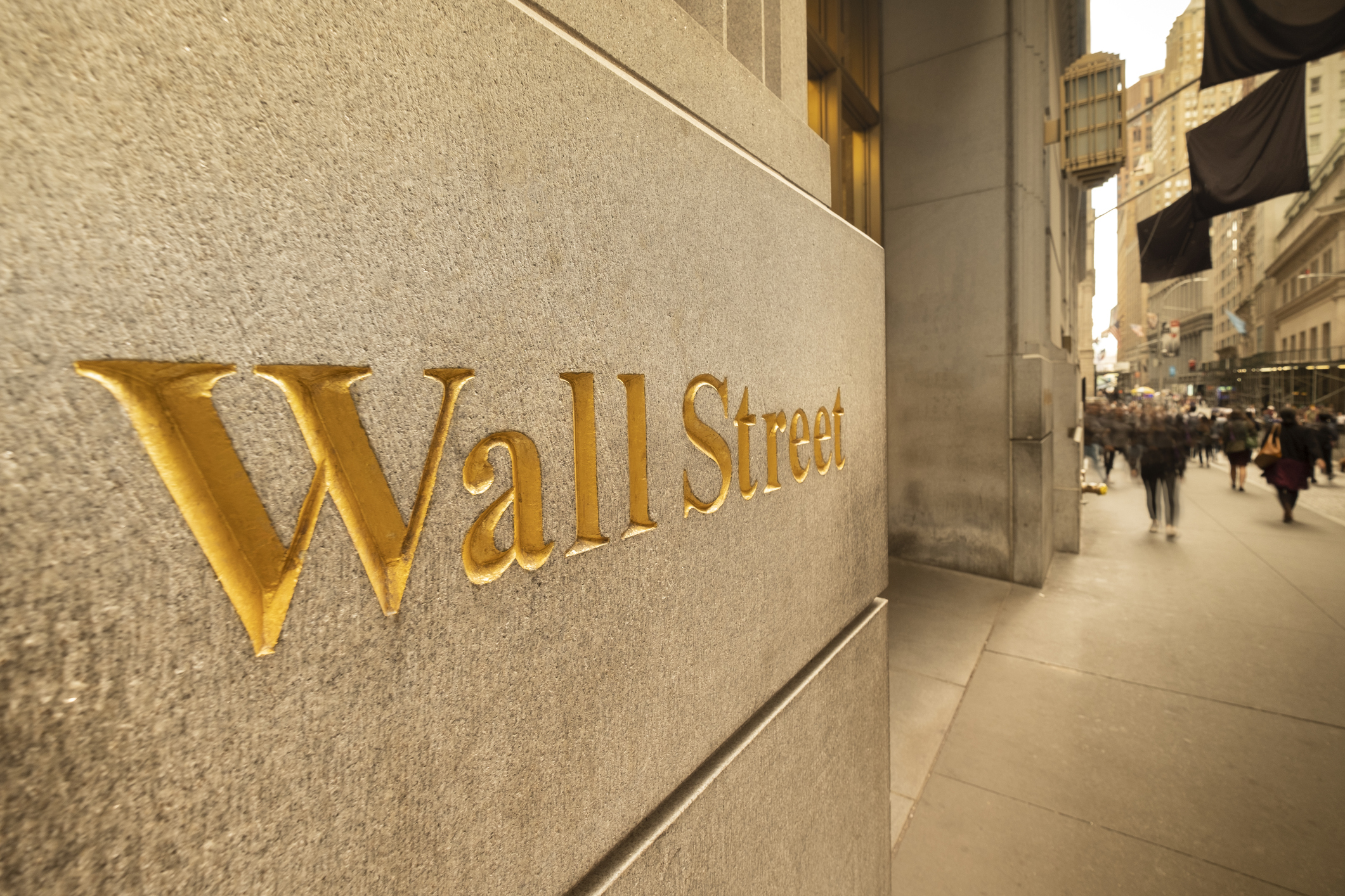 The phrase, Wall Street, engraved in gold color on the side of a building in New York's financial district.