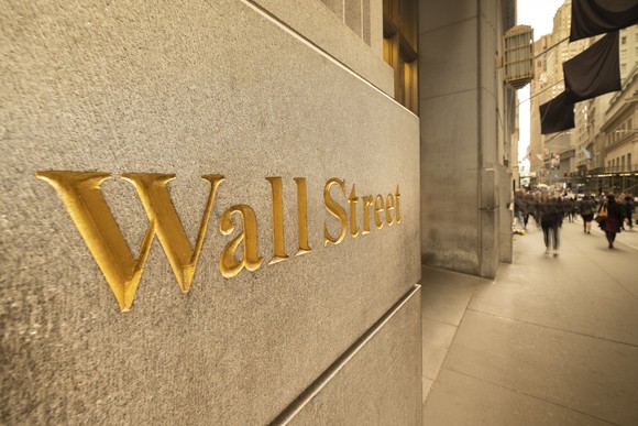 The phrase, Wall Street, engraved in gold color on the side of a building in New York's financial district.