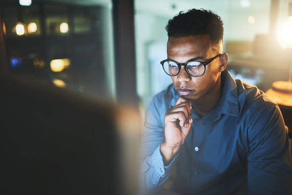Developer looking things over on their computer while contemplating which decision to make.