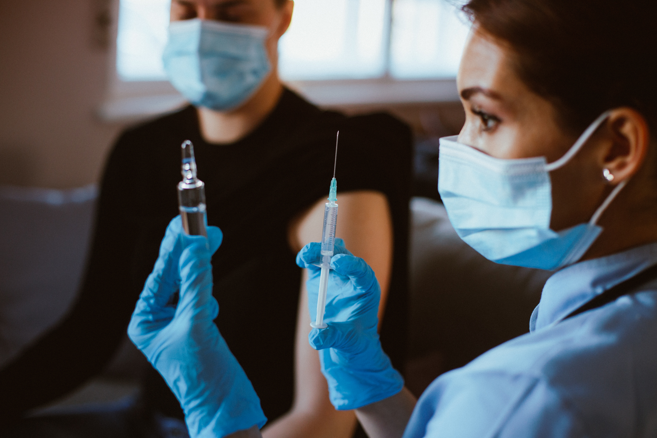 A healthcare worker prepares to vaccinate an individual.