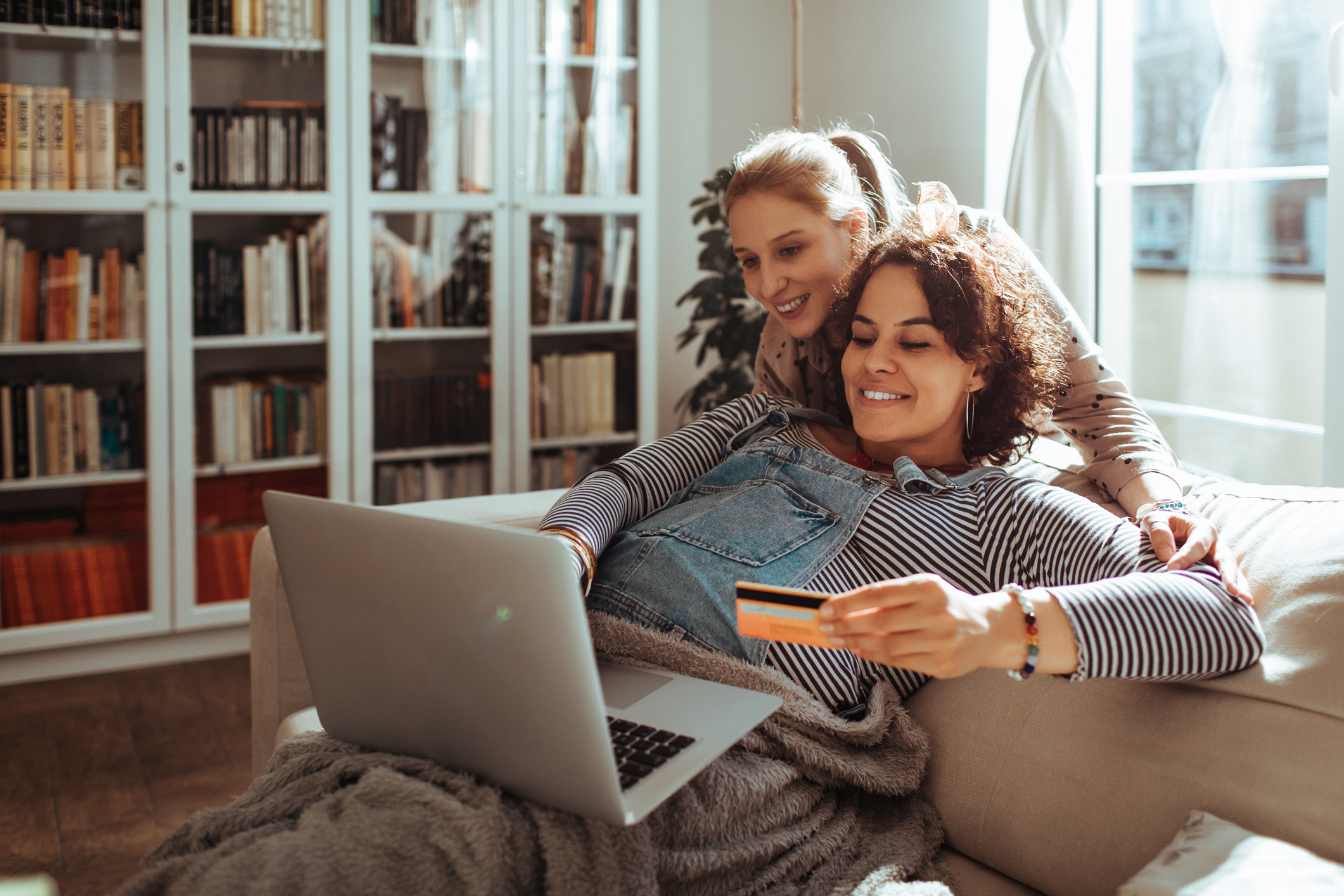 Two people in a living room shop online.