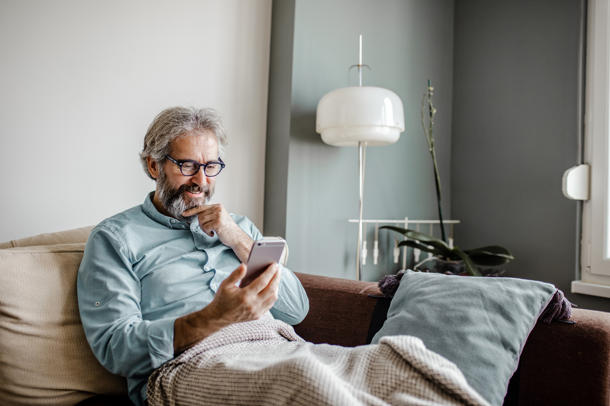 A person on a couch looking at a mobile phone.