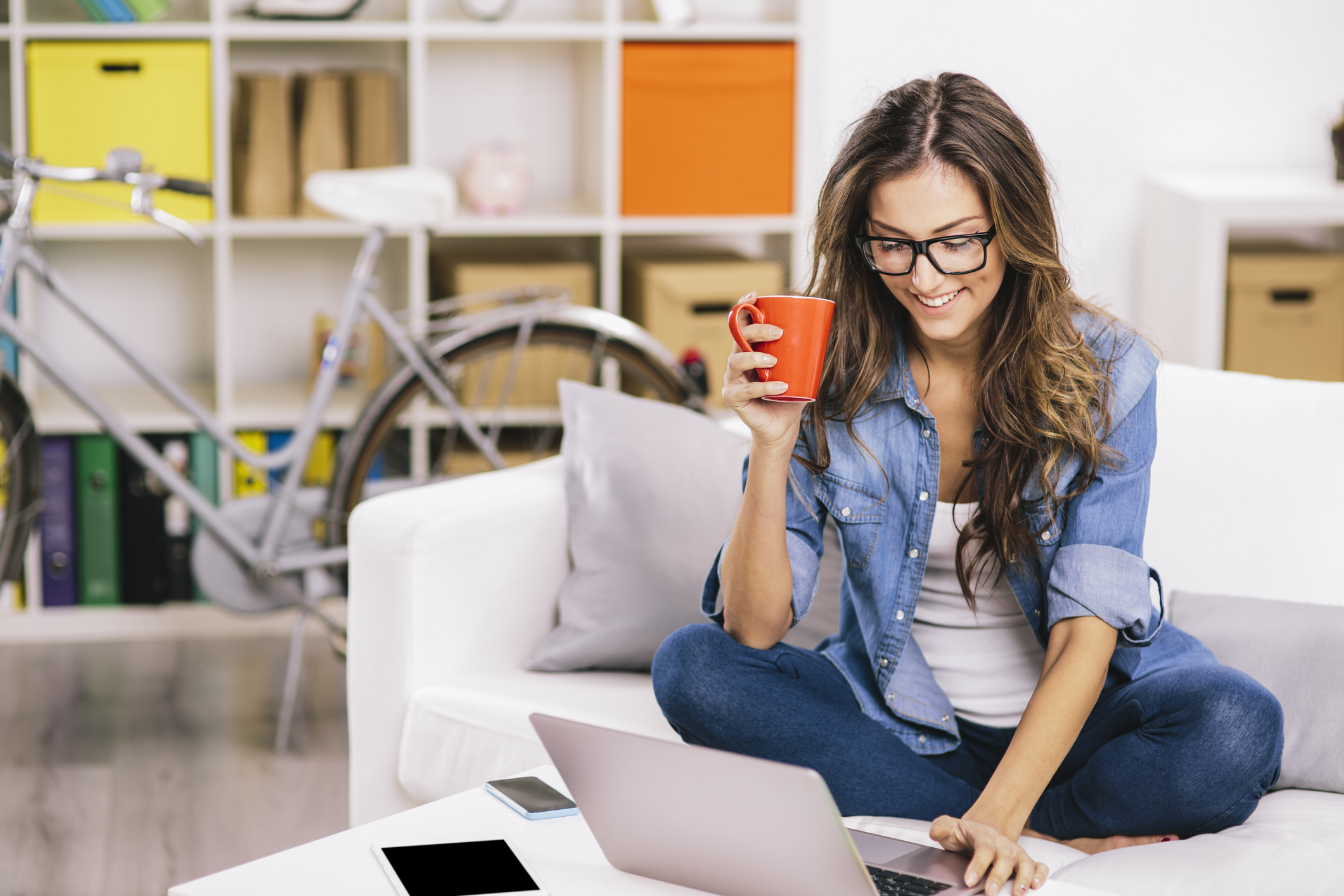 A person holds a mug while using a laptop.