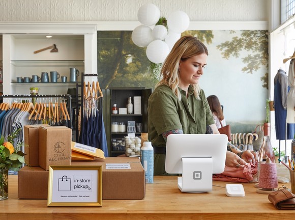 A business person uses a Square point-of-sales device from Block.