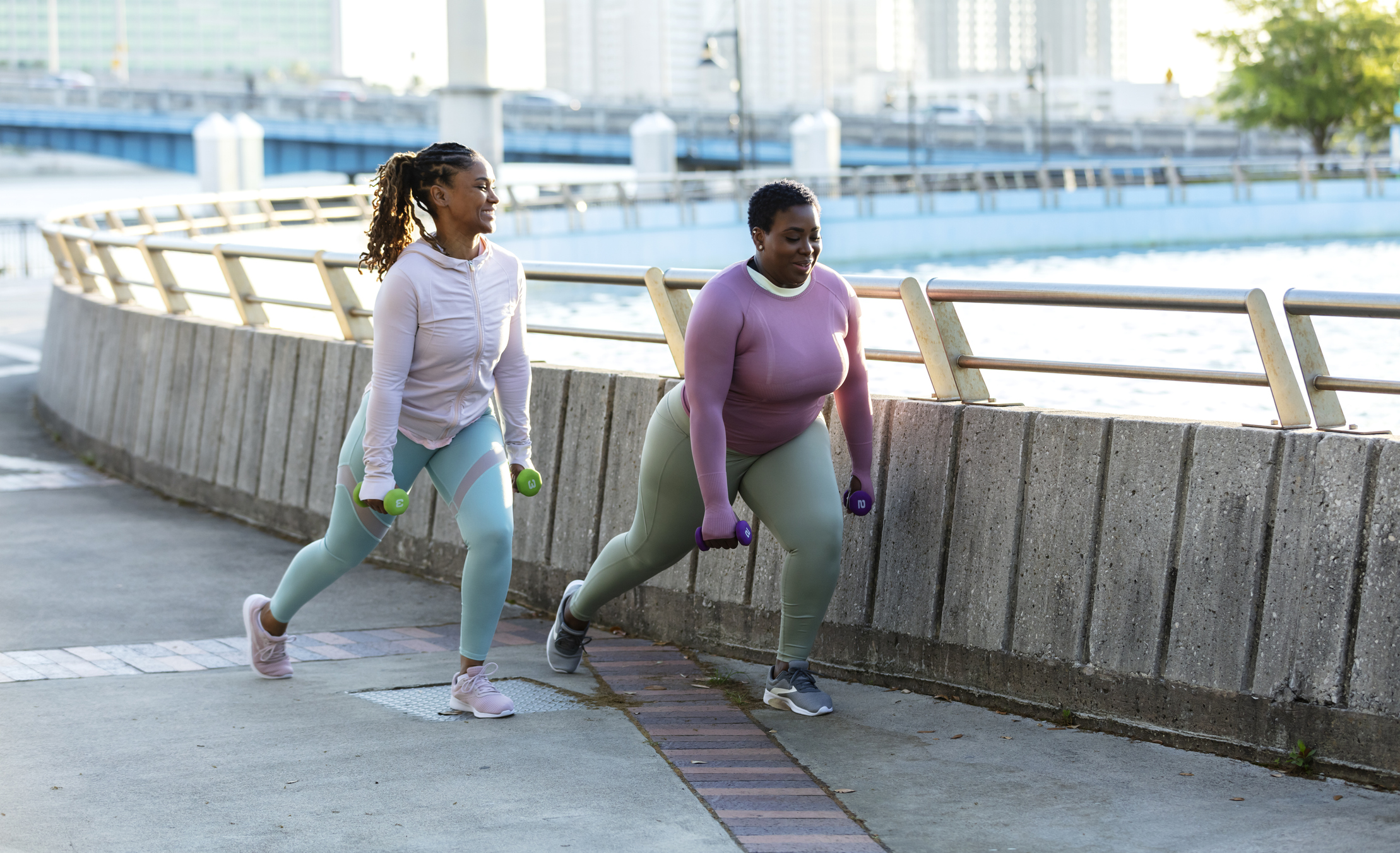 Two people exercising and doing lunges in the park.