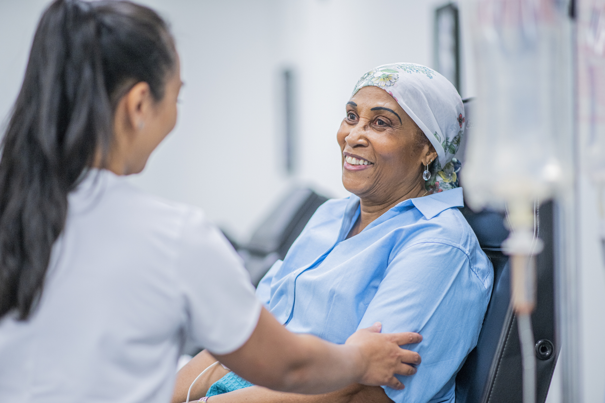 A healthcare worker touches the arm of a patient receiving an infusion.