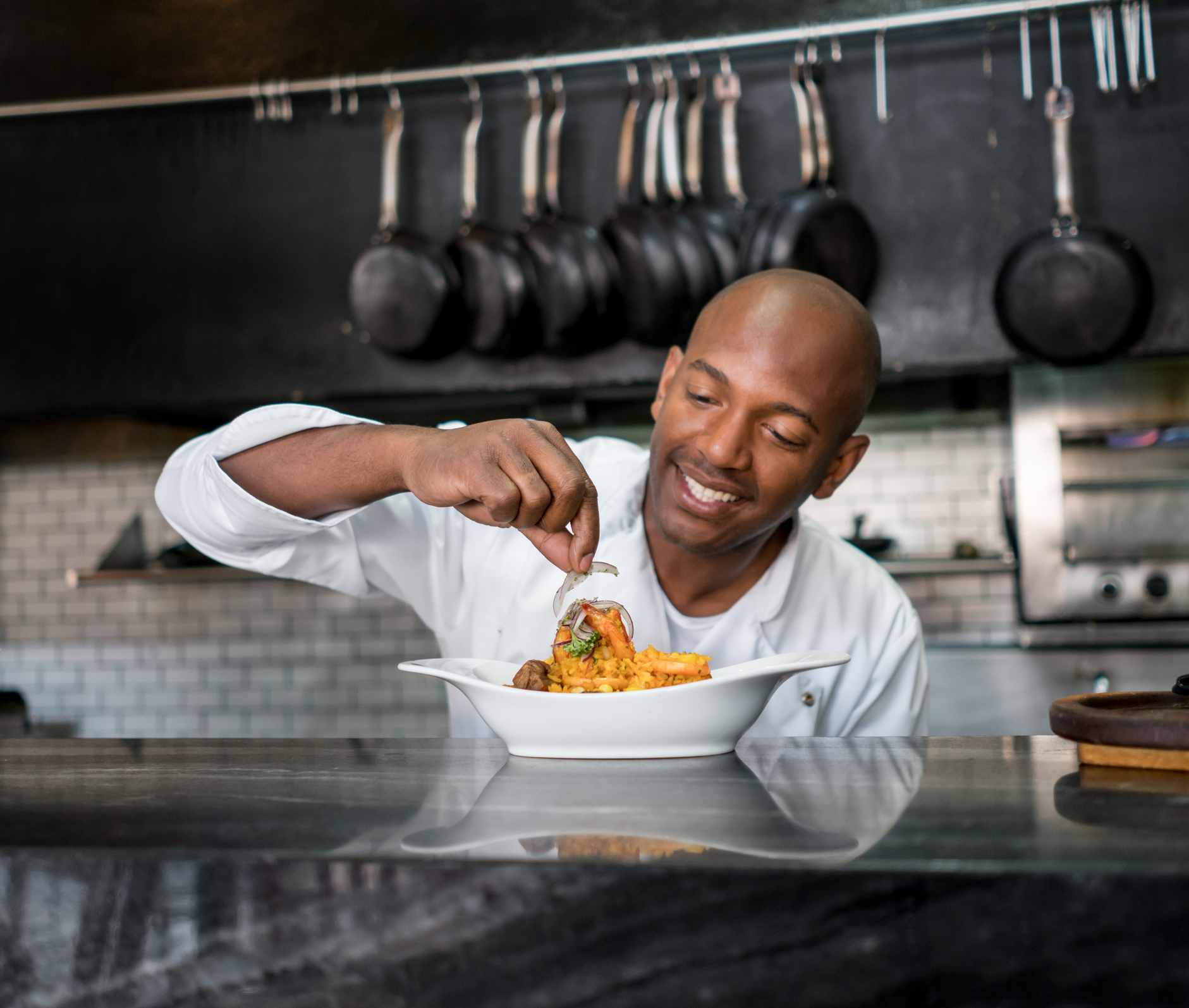 A chef putting garnish on a dish.