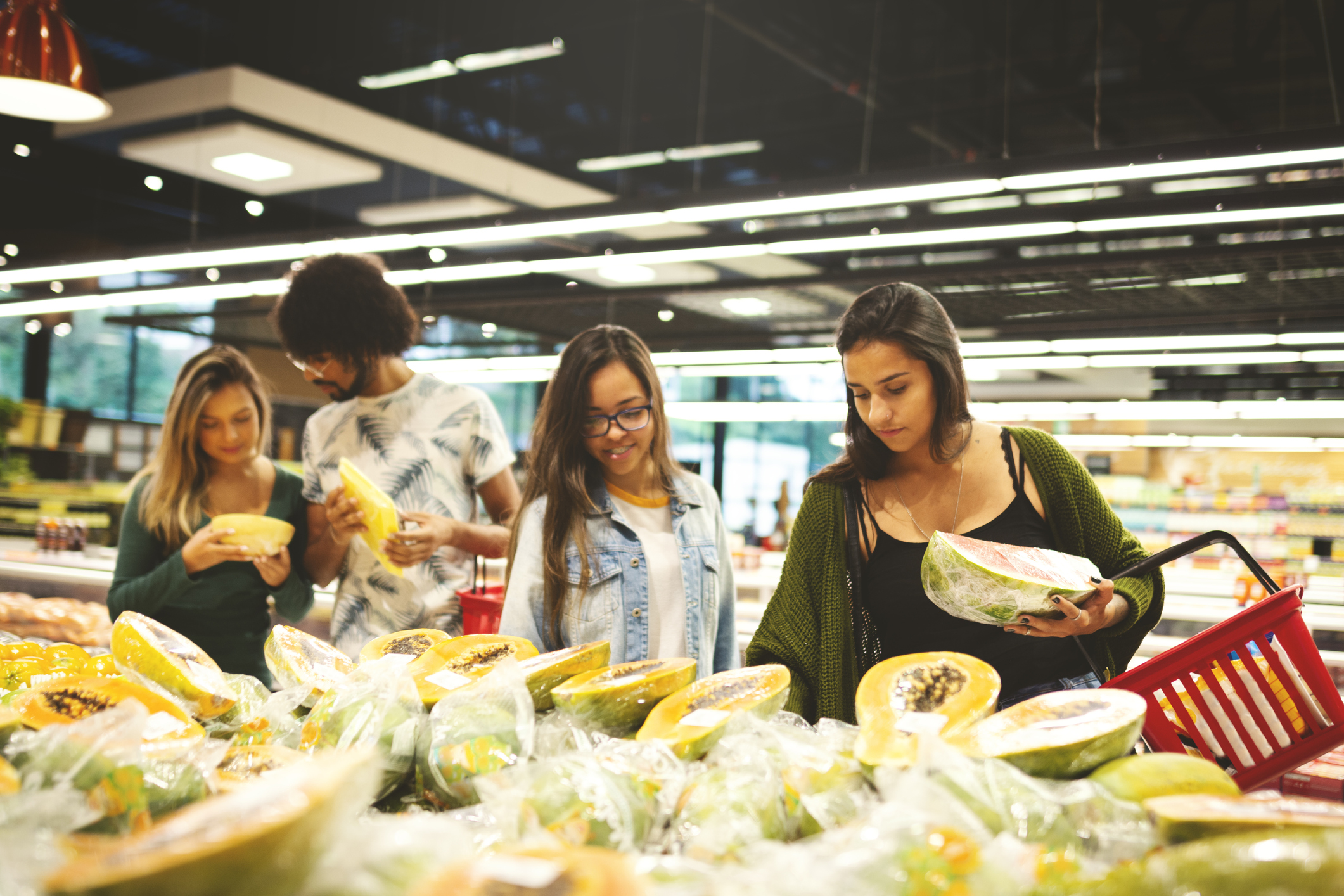 A group of friends shopping in the produce section of a grocery store.