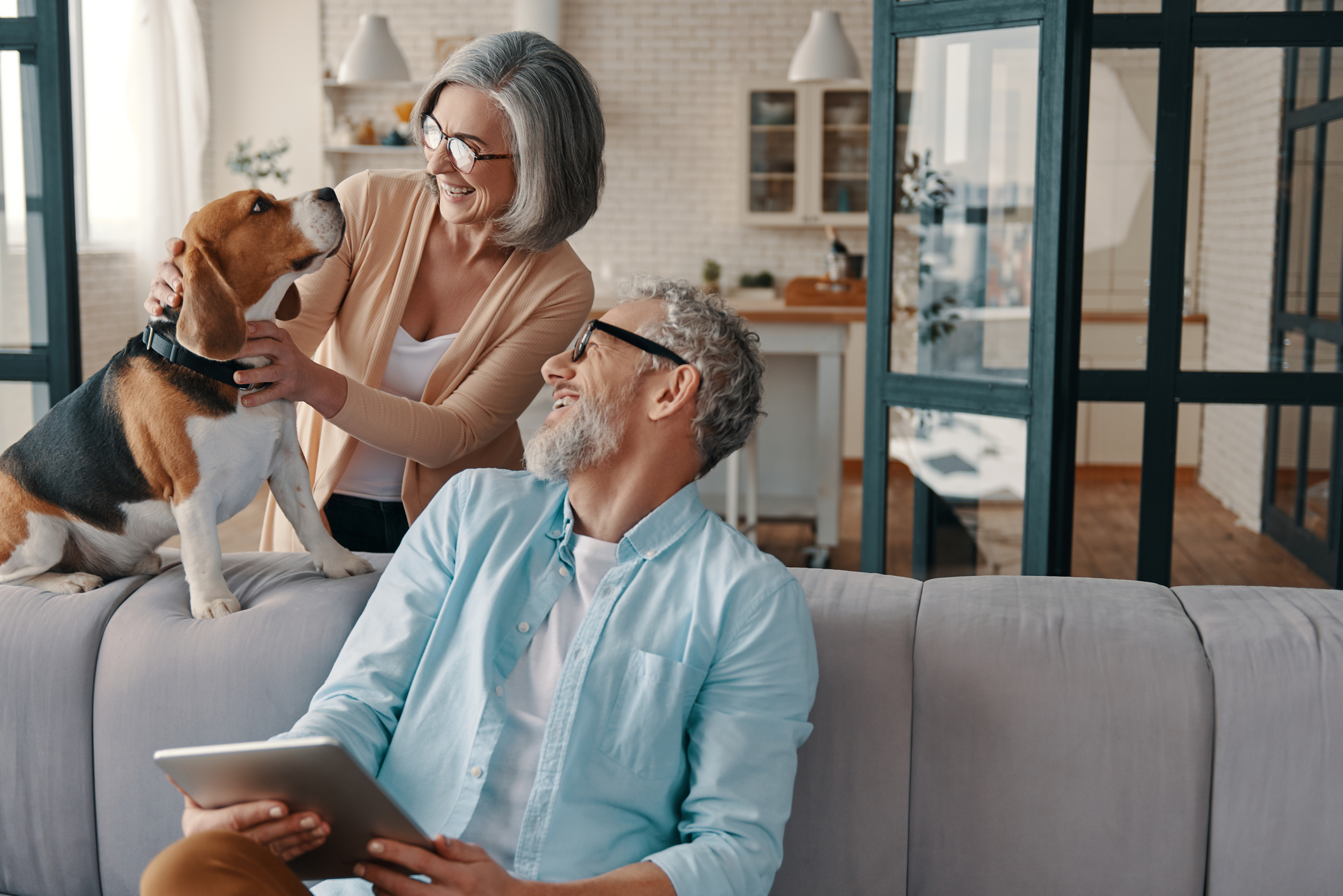 Two people inside a home smiling at a dog.