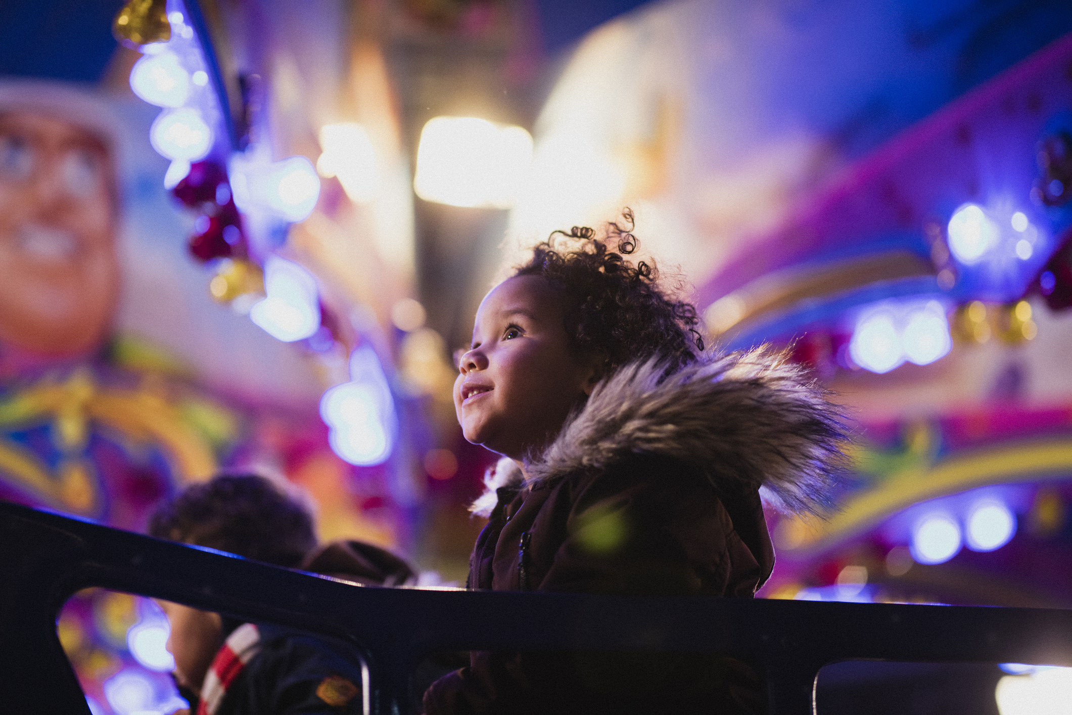 Young kid looking up at something in a theme park at night.
