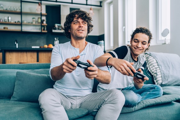 Two people playing video games while sitting on couch.