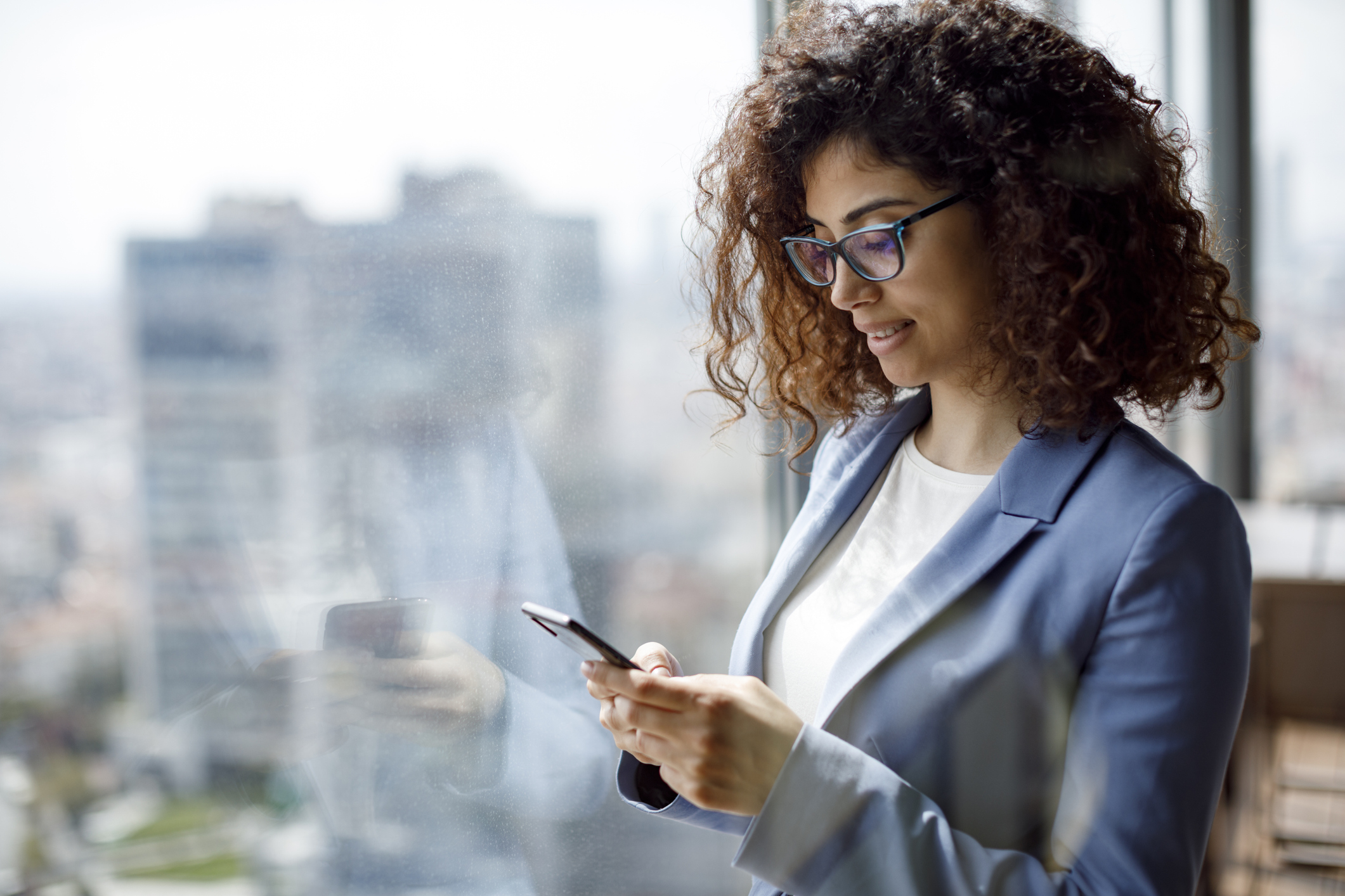 Well dressed person in an office looking at a smartphone