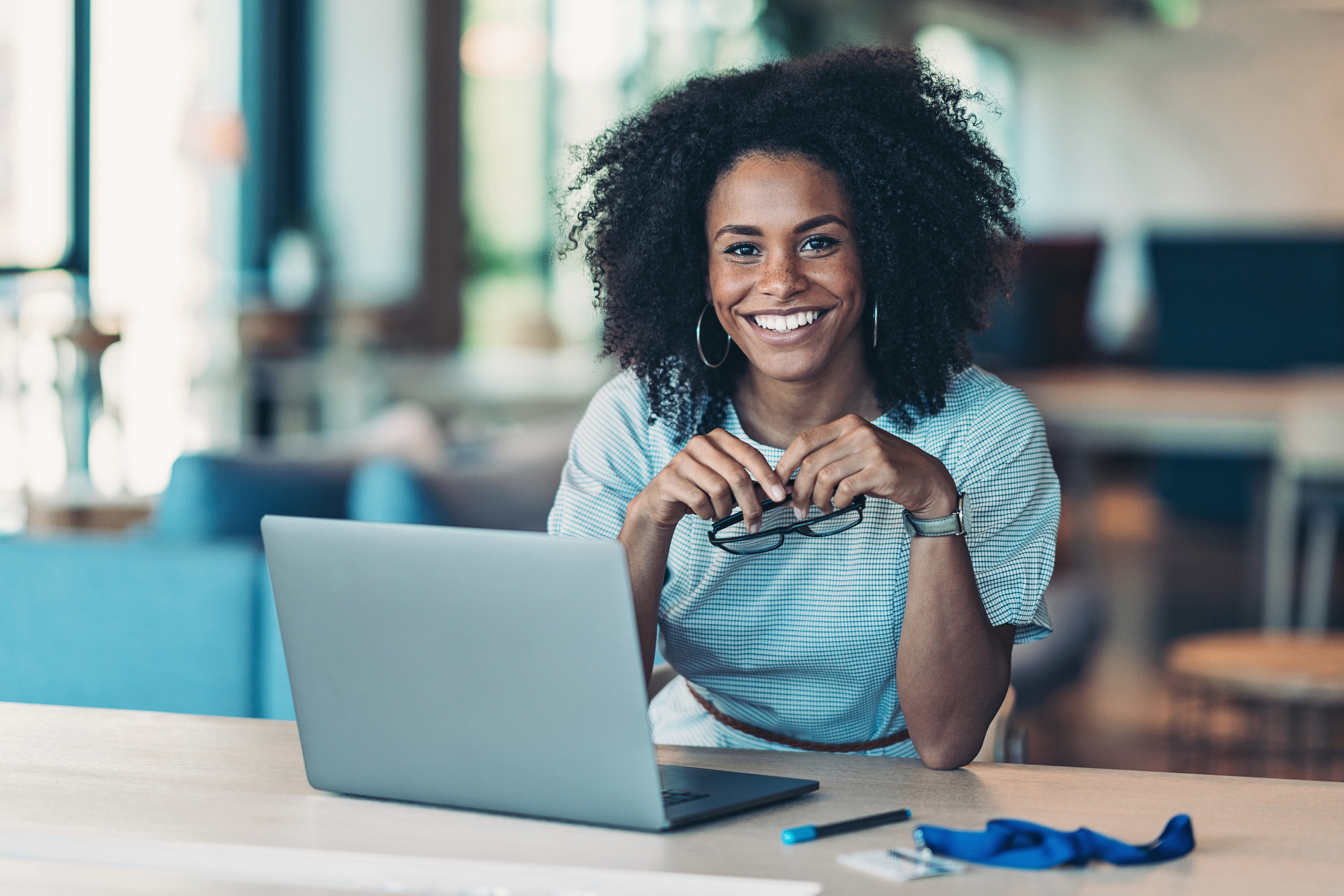 A smiling person at a laptop.