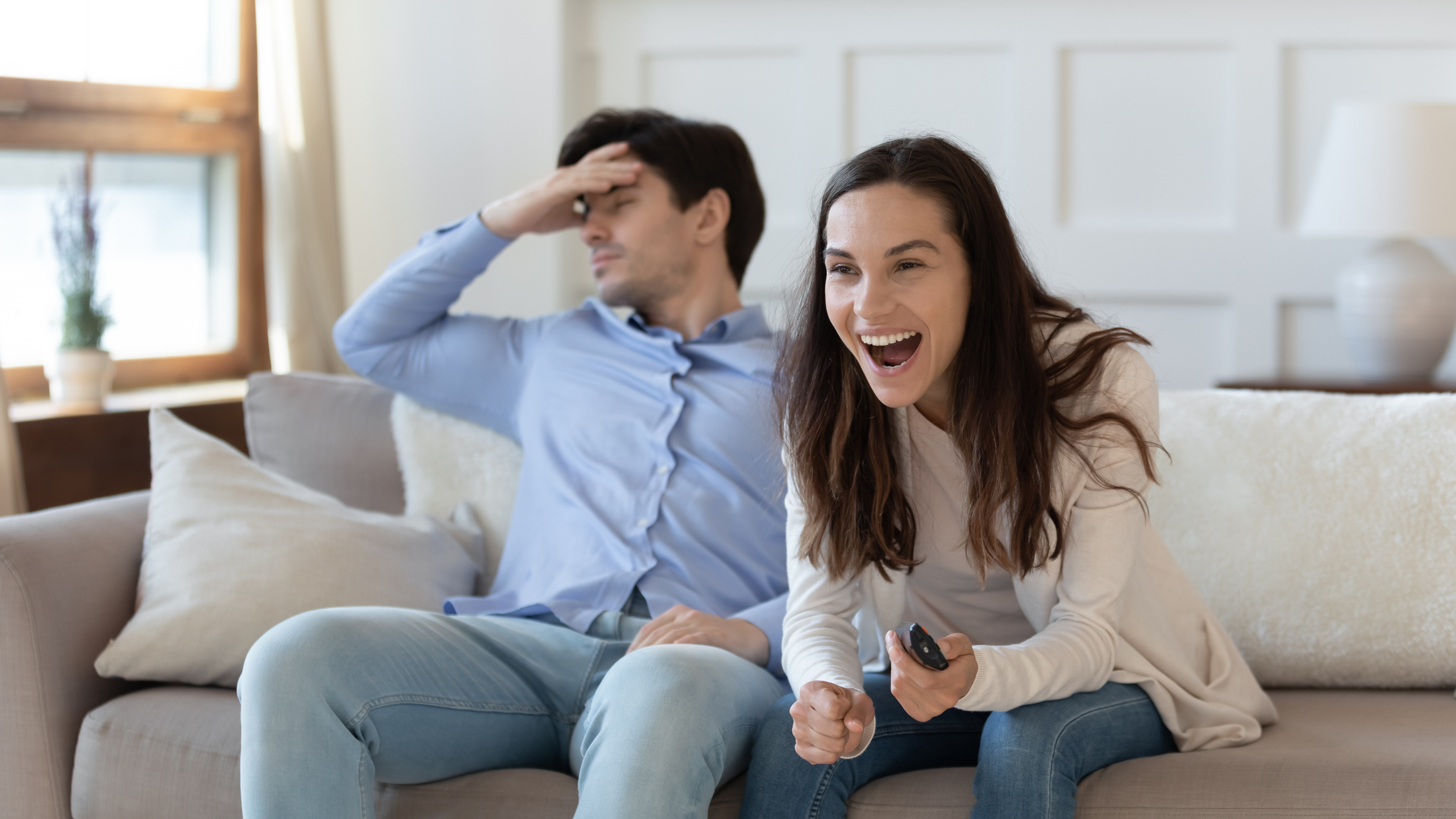 One upset person and one happy person sit on a couch.