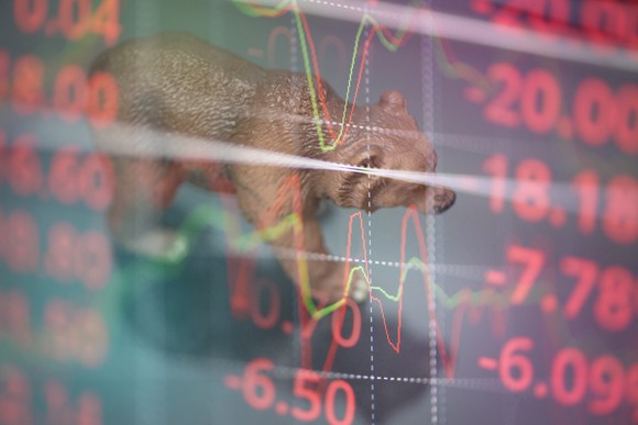 A bear figurine walks on a digital stock index chart.