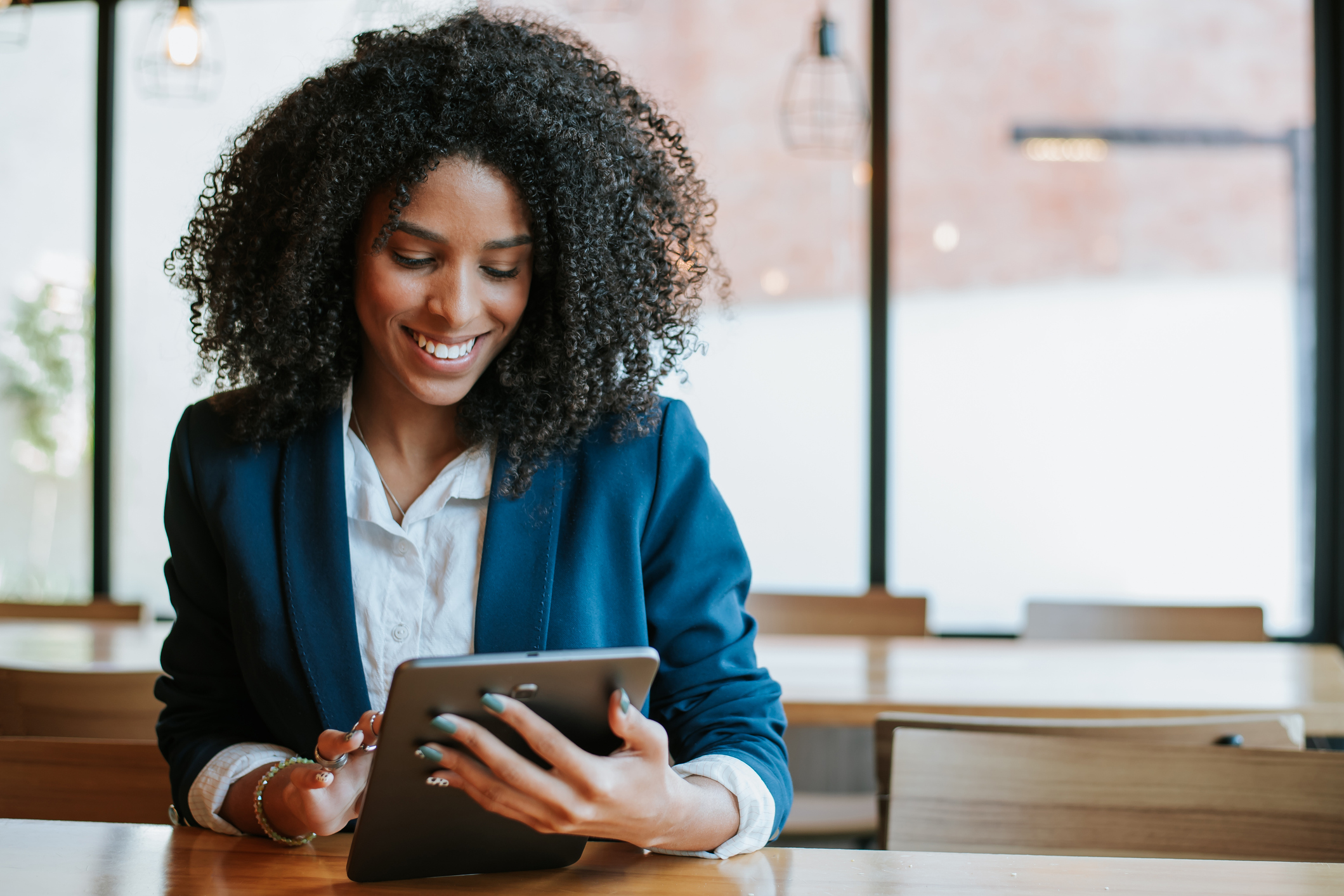 A smiling person looks at a tablet.