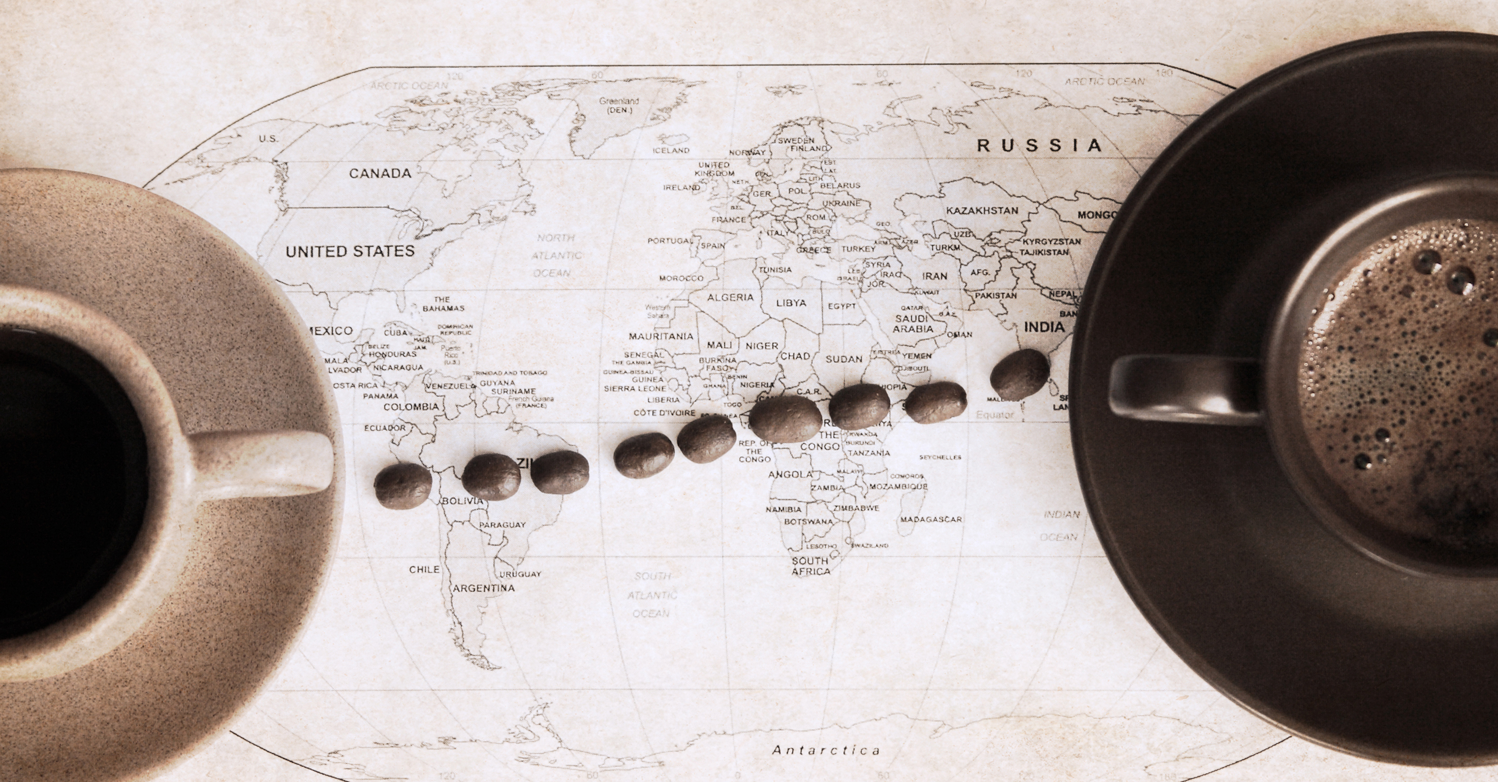 Two cups of coffee on a map of the world with a trail of beans connecting east to west.