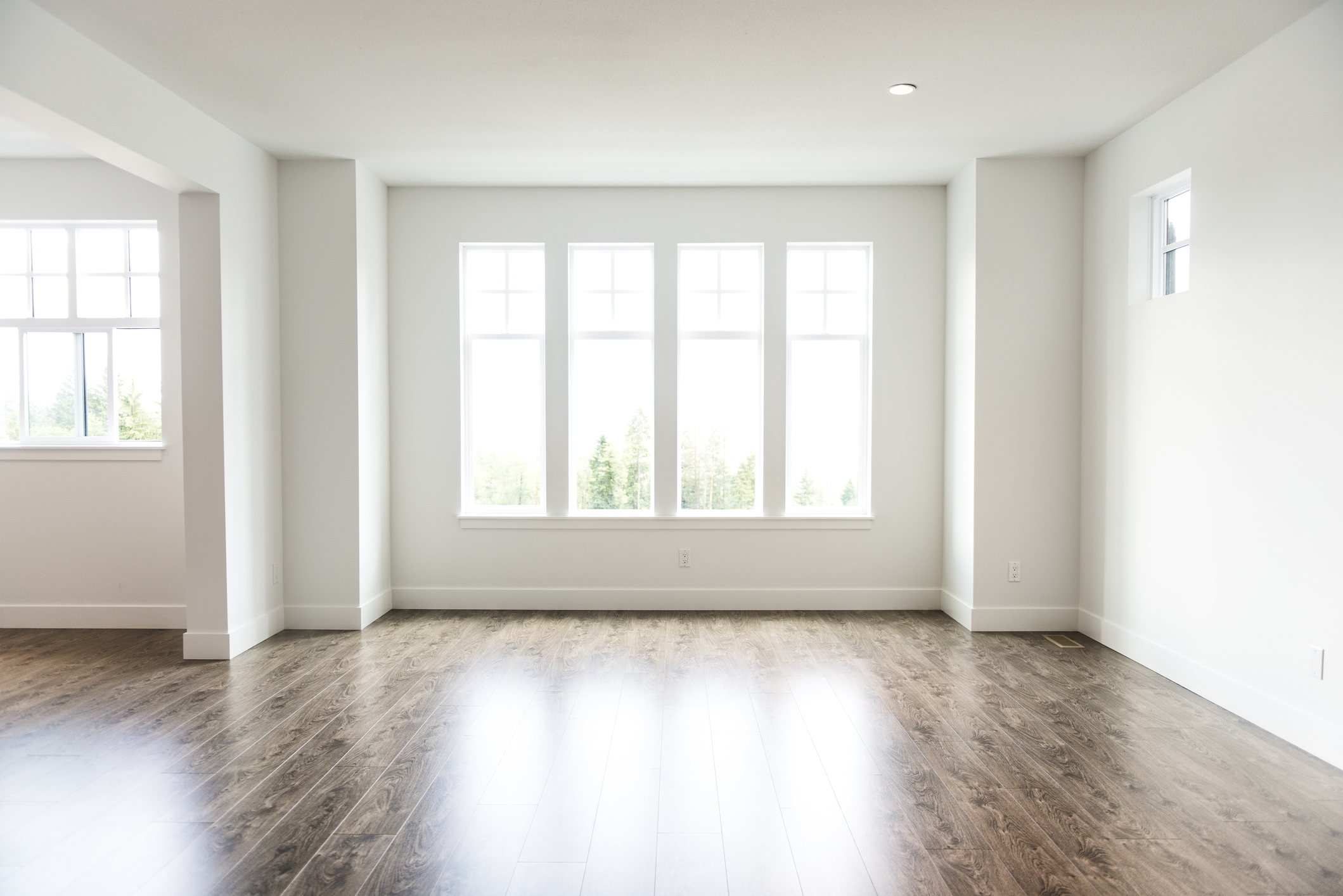 An empty open-concept space that's filled with natural sunlight from the windows.