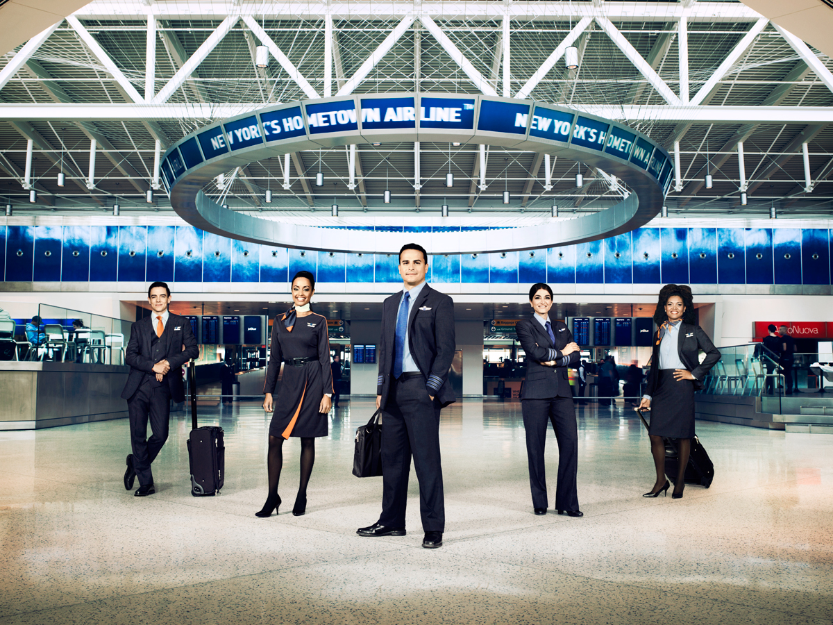 A JetBlue flight crew posing for a photo in an airline terminal.