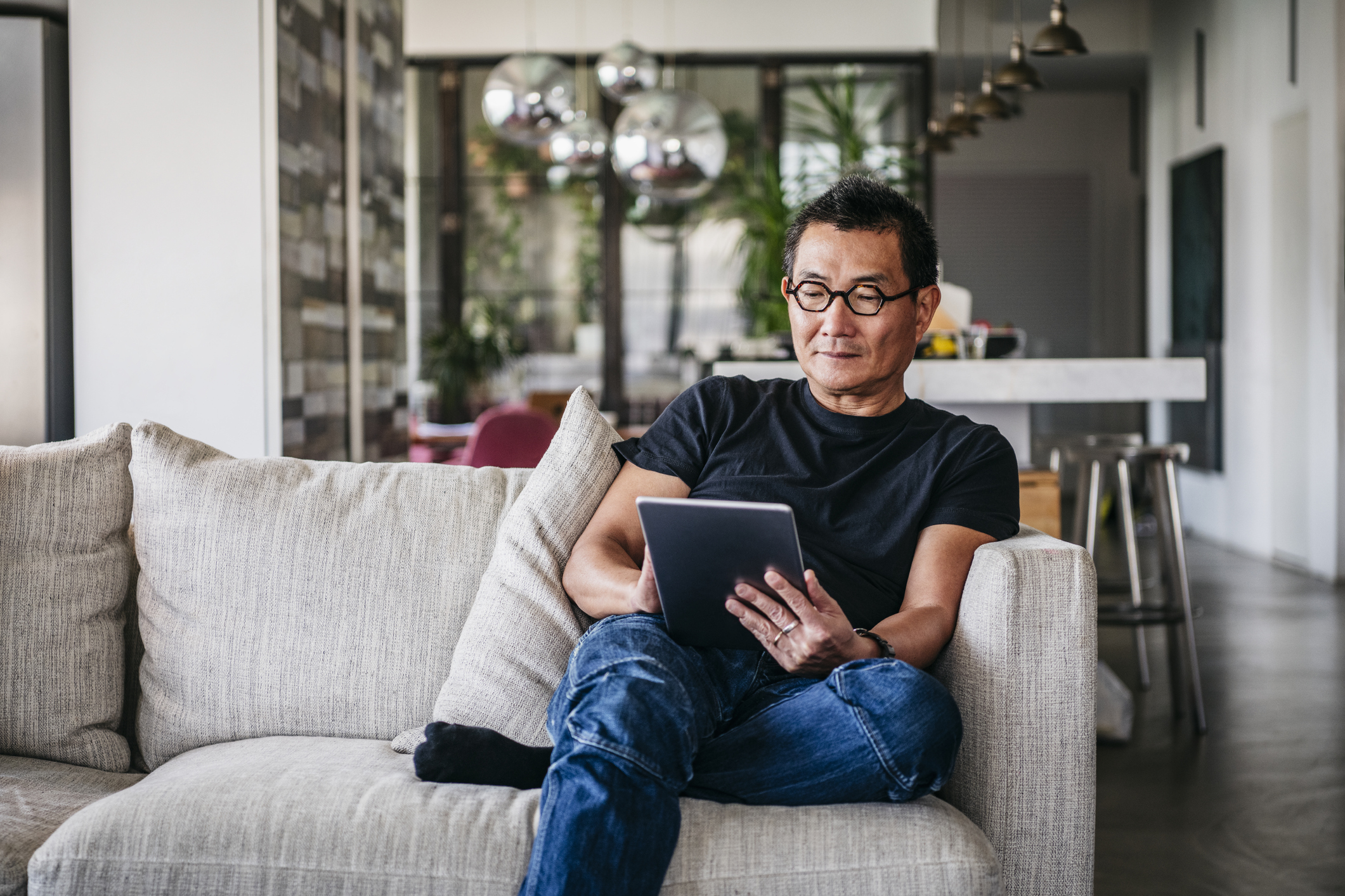 Man sitting on a couch holding a tablet.