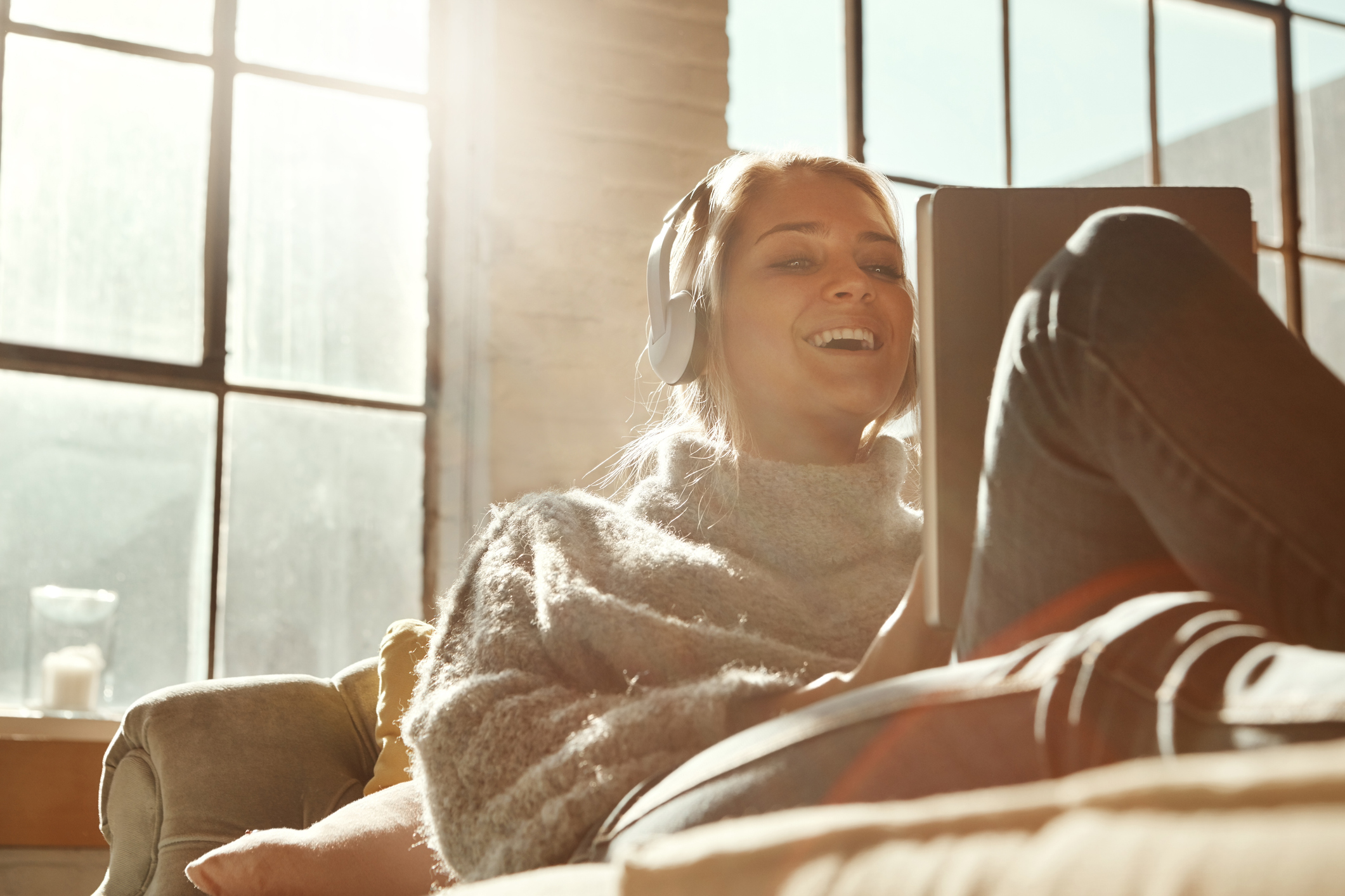 A person listening to music with headphones while stretched out on a couch.