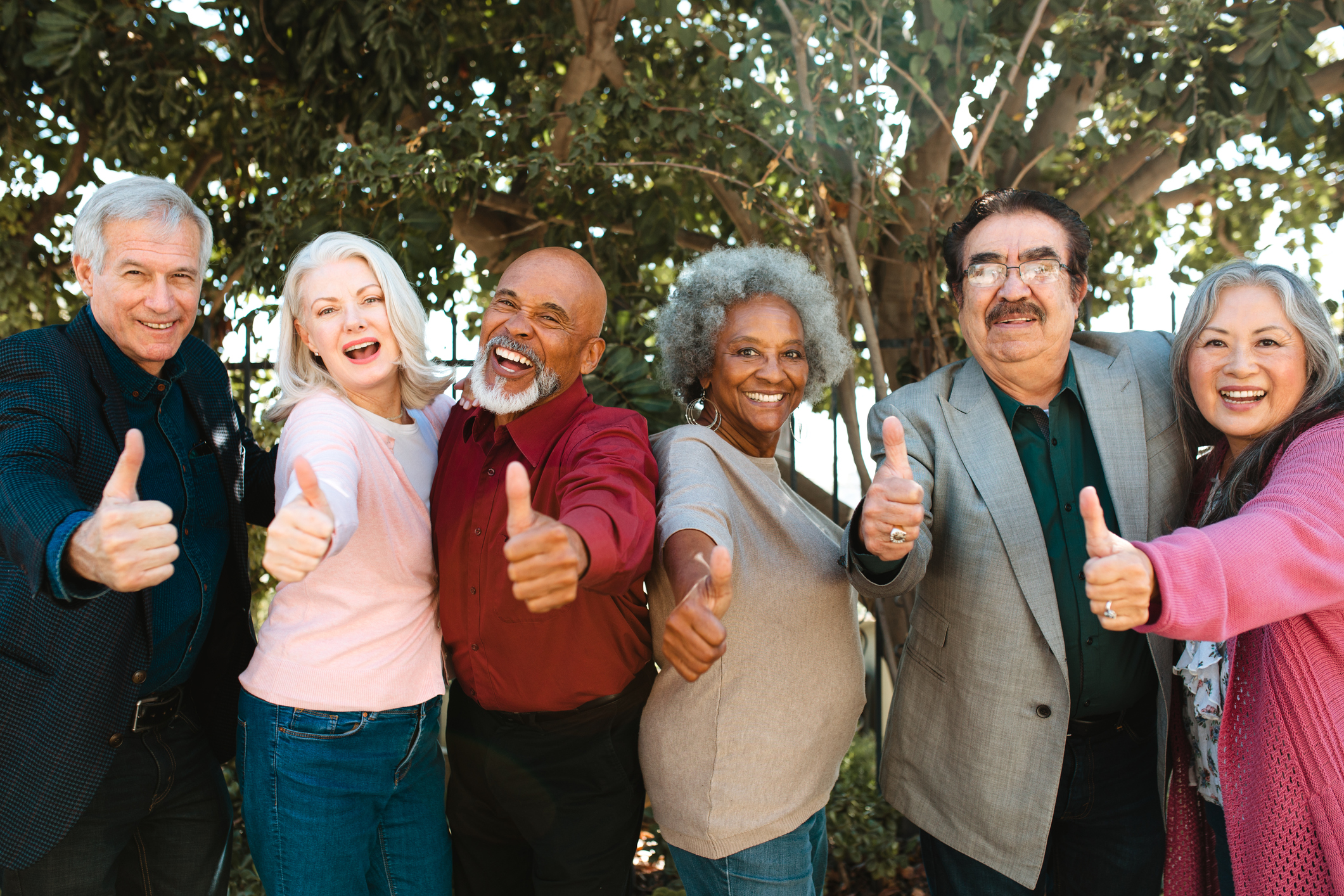 A line of people holding their thumbs up.