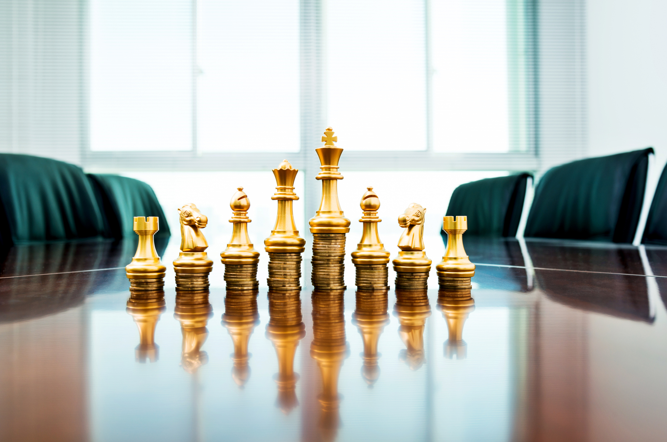 Golden chess pieces placed atop stacks of coins.