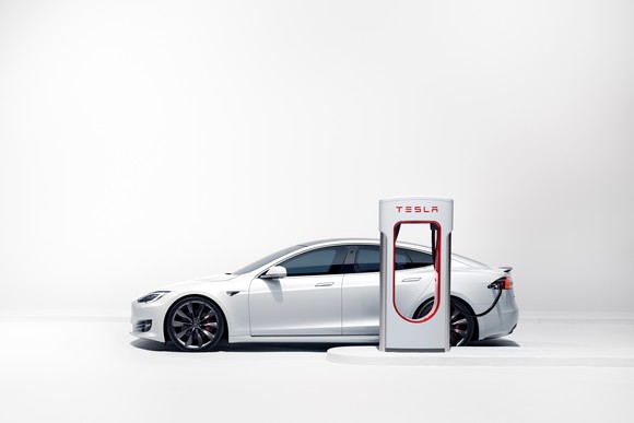 White Tesla EV at supercharger. 
